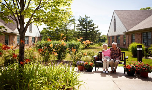 A cheerful elderly couple enjoying a sunny day in their garden, surrounded by vibrant flowers and greenery.