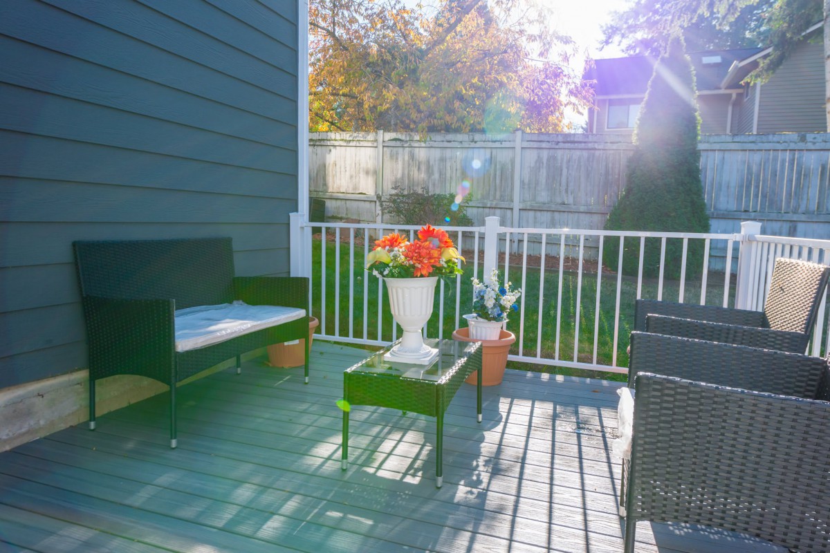 A cozy patio with outdoor seating and a table adorned with vibrant flowers, bathed in warm sunlight.