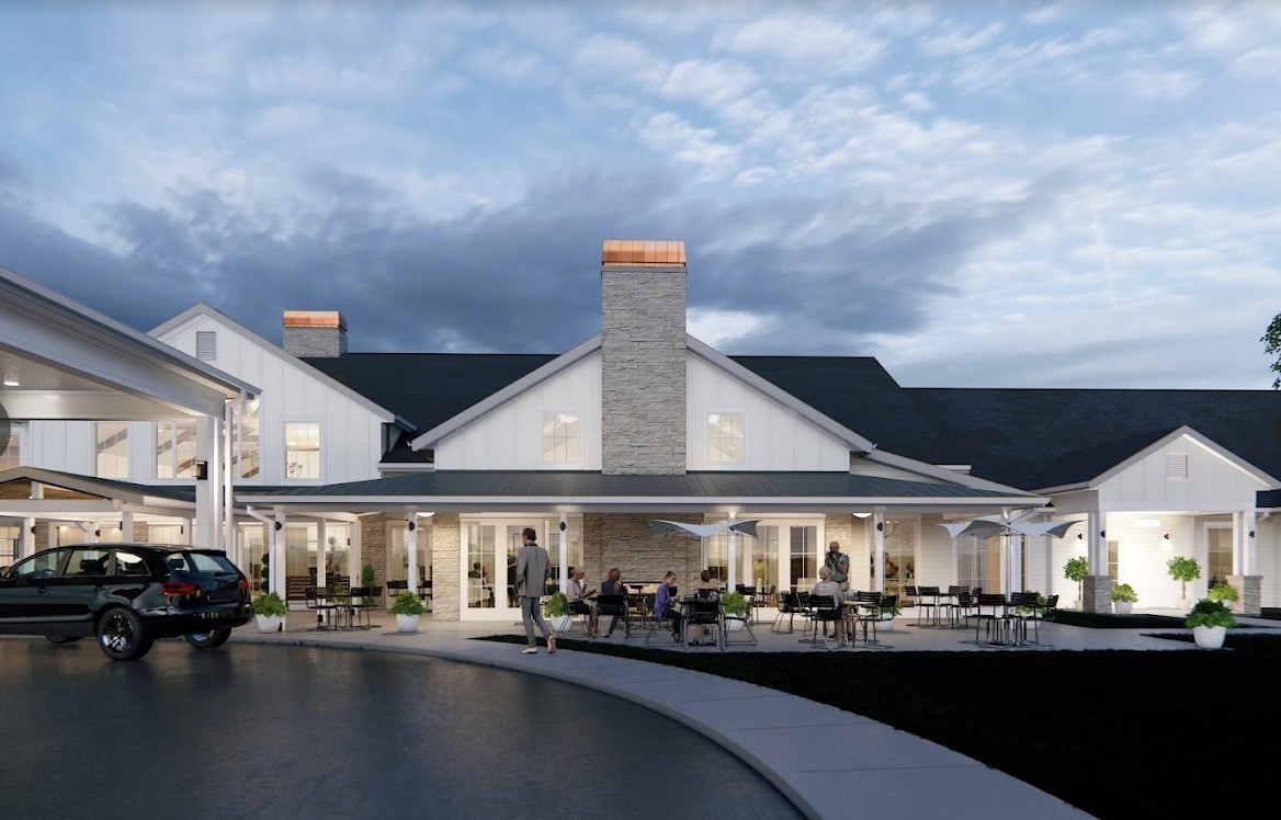 A large house with multiple chimneys and a spacious porch in the evening.