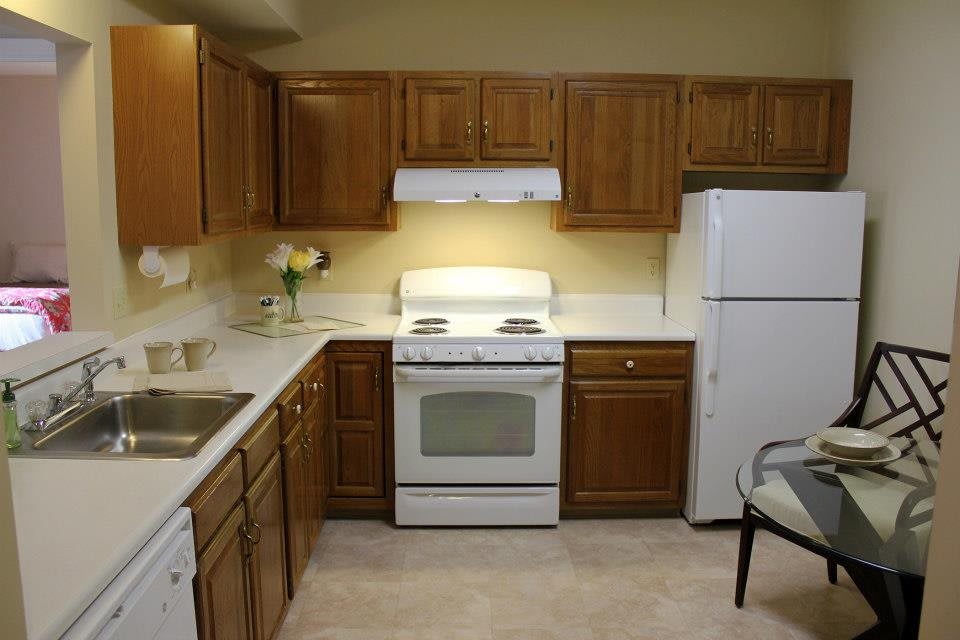 A cozy kitchen with wooden cabinets, featuring a stove, oven, and refrigerator.