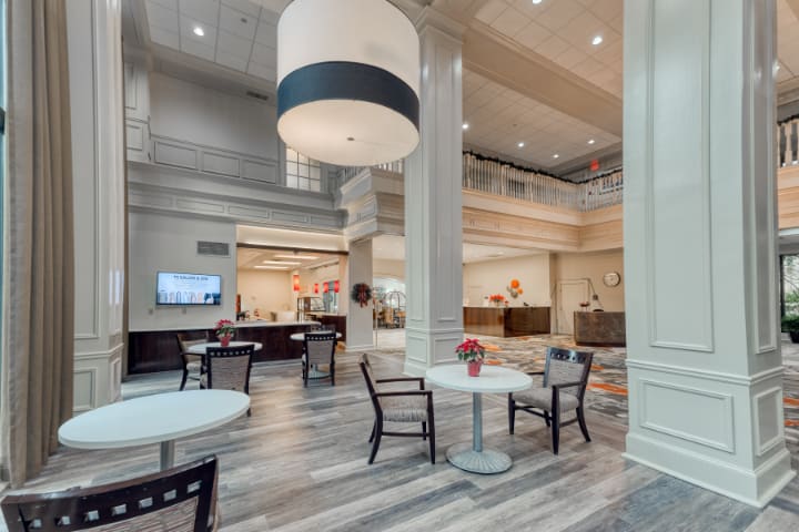 A spacious hotel lobby with modern decor, featuring a seating area and a large chandelier.