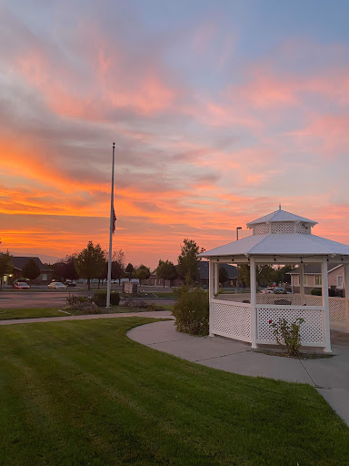 A serene sunset casting vibrant colors over a gazebo in the park.