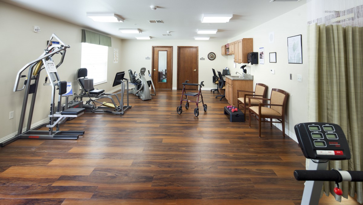 A physical therapy room equipped with exercise machines and a walker for rehabilitation.