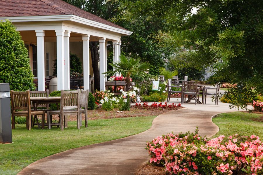 A beautifully landscaped garden with a pathway leading to a gazebo, surrounded by vibrant flowers and outdoor seating.