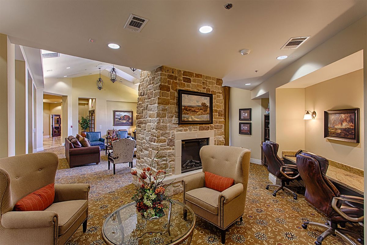 A cozy living room with a stone fireplace, comfortable seating, and warm lighting.