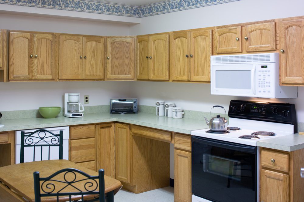 A kitchen with wooden cabinets and various appliances, including a microwave, stove, coffee maker, and toaster.