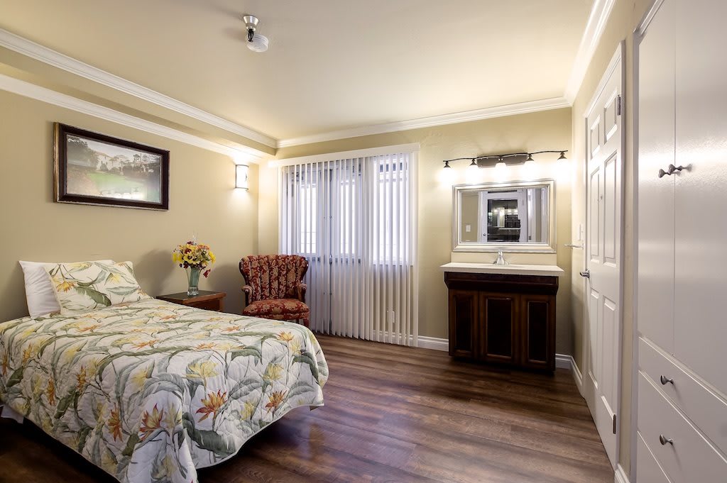 A cozy bedroom with a floral bedspread, wooden flooring, and elegant furnishings.