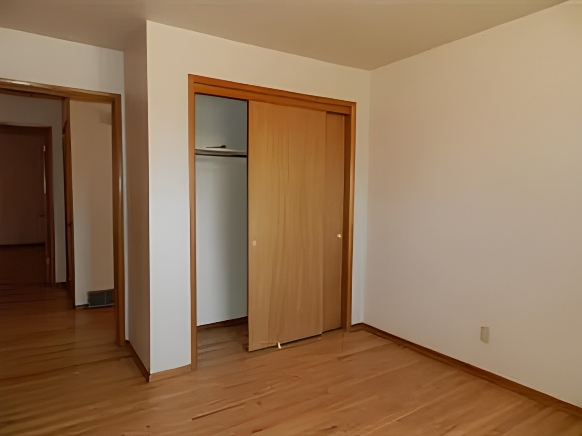 An empty room with a wooden floor and a sliding closet door.