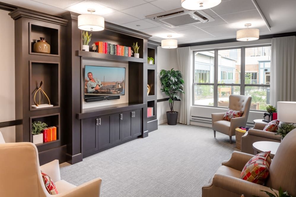 A modern living room with a large television, built-in shelving, and comfortable seating.