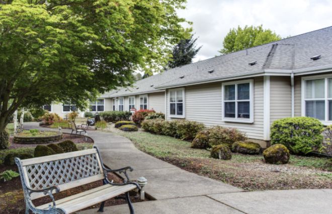 A peaceful residential area with a sidewalk, benches, and well-maintained landscaping.