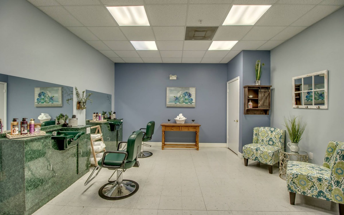 A minimalist salon interior with haircut chairs and a small waiting area.