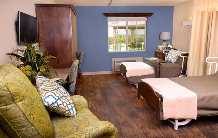 A cozy bedroom with two beds, warm decor, and a large window.