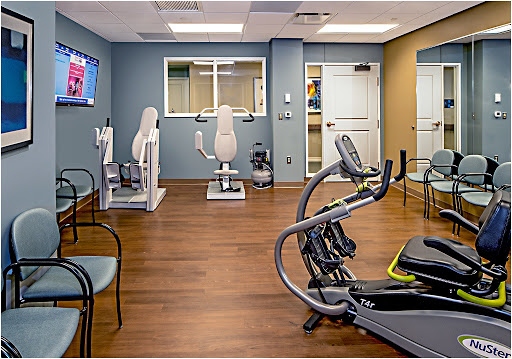 A well-equipped physical therapy gym featuring various exercise machines and a welcoming atmosphere.