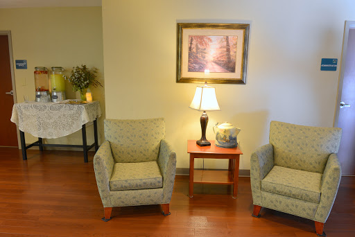A cozy living room setup with two chairs, a lamp, and artwork on the wall.