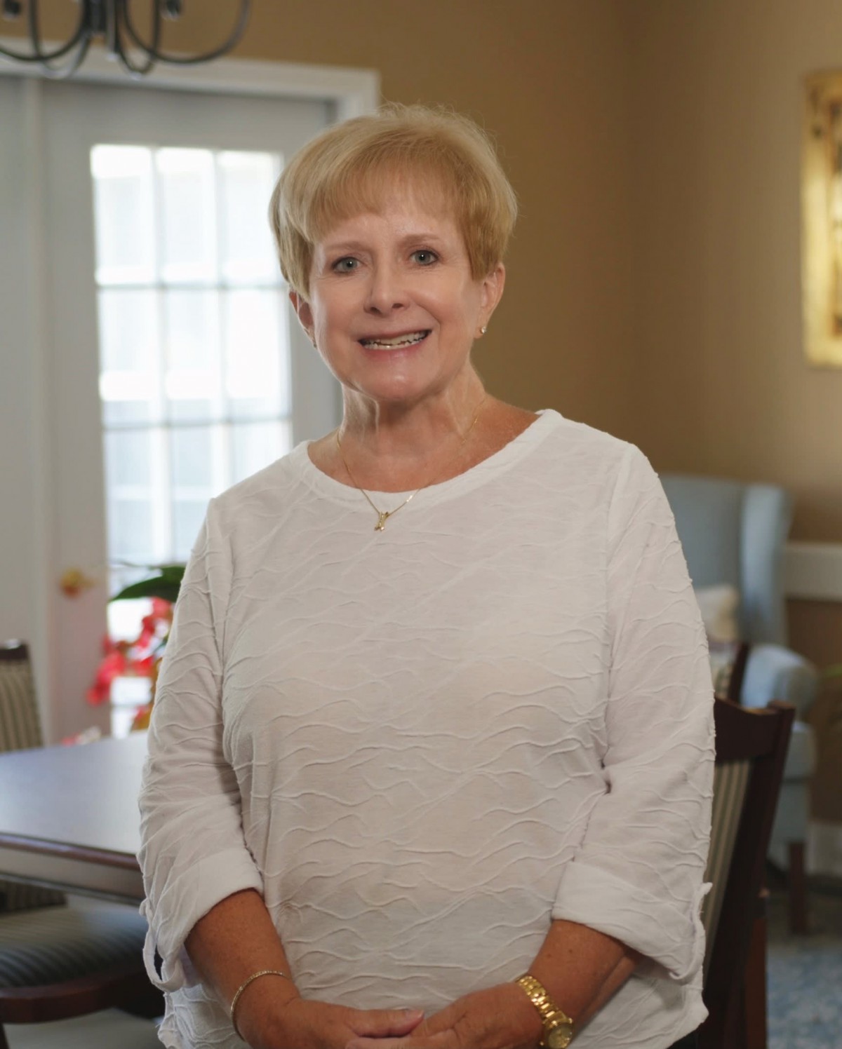 A smiling woman standing indoors in casual clothing.