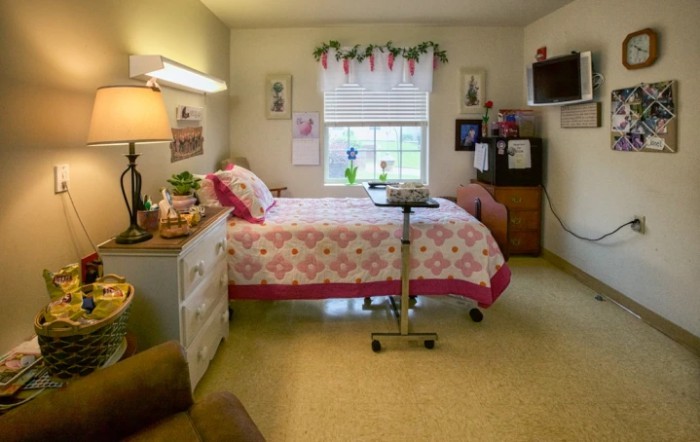 A cozy bedroom with a single bed, floral quilt, and decorative touches.