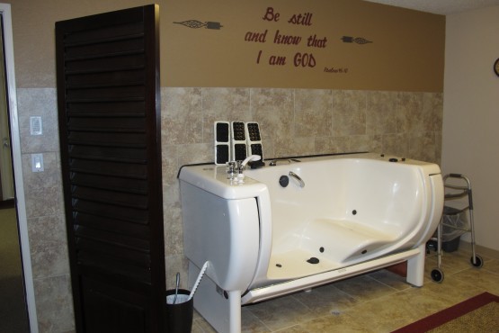 A modern bathroom featuring a jacuzzi tub against a tiled wall with decorative text.