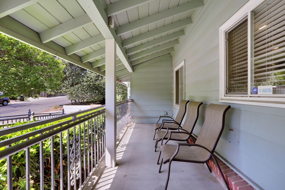 A covered porch with outdoor seating and a railing, providing a comfortable space for relaxation.