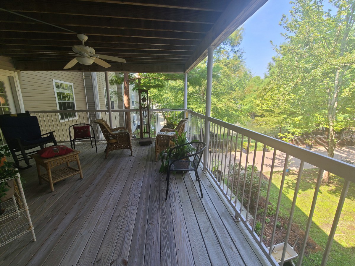 A cozy porch with outdoor furniture overlooking a lush green landscape.