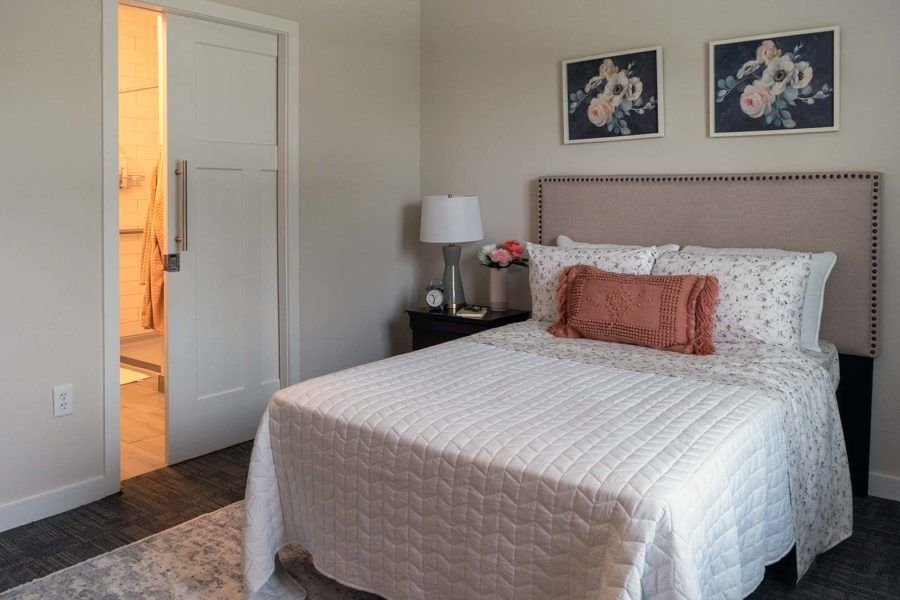 Cozy bedroom with a neatly made bed, decorative pillows, and wall art.
