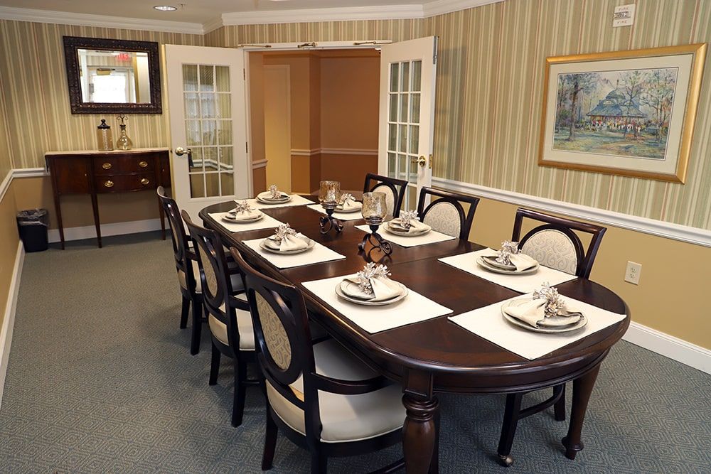 A formal dining room setup with a long table and chairs, elegantly arranged with place settings.