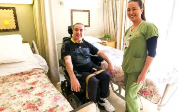 A nurse providing care to a patient in a wheelchair within a hospital room.