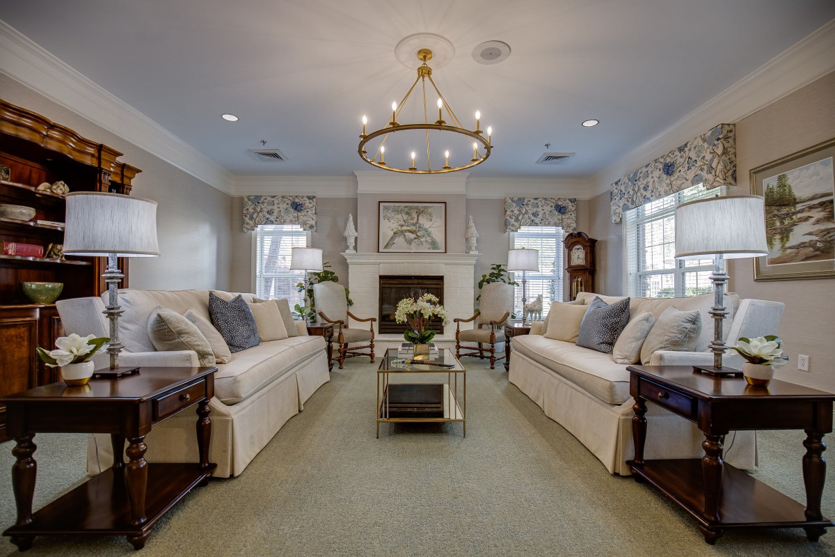 A beautifully decorated living room with sofas, a chandelier, and a fireplace.