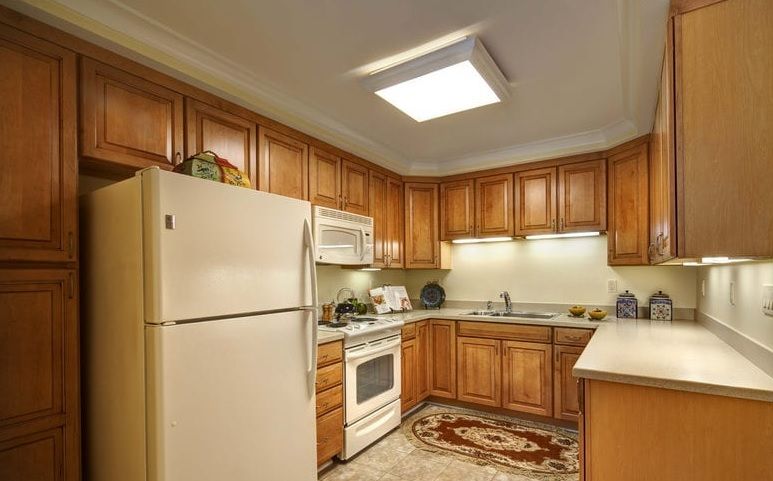 A cozy kitchen with wooden cabinets, equipped with a refrigerator, oven, and microwave.