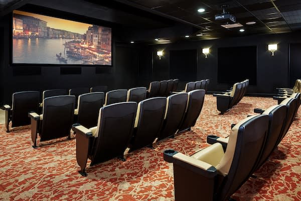 An empty theater room with a large screen and comfortable seating.
