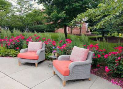 Cozy outdoor seating area with cushioned chairs and vibrant flowers.