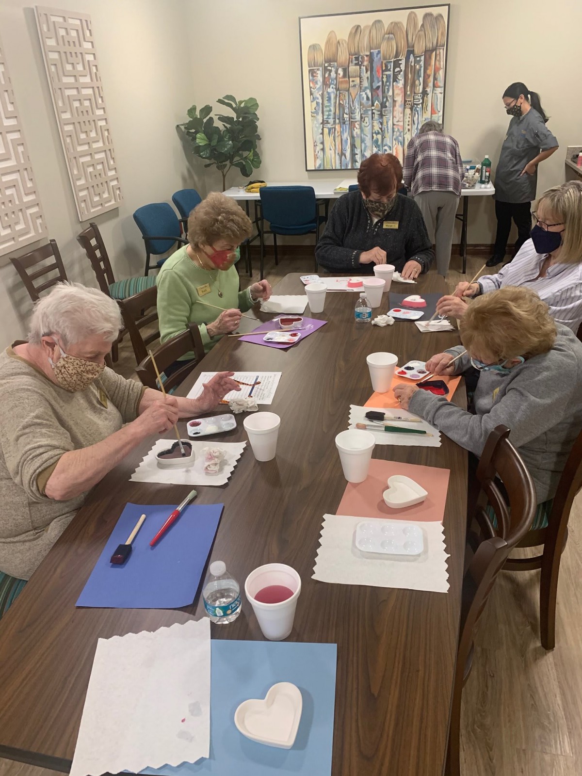 A group of seniors engaging in a crafting activity around a table indoors.