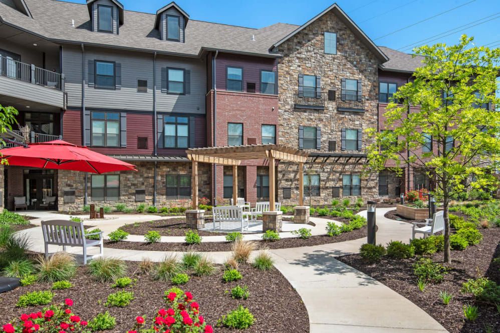 A modern residential building with a landscaped garden and outdoor seating area.