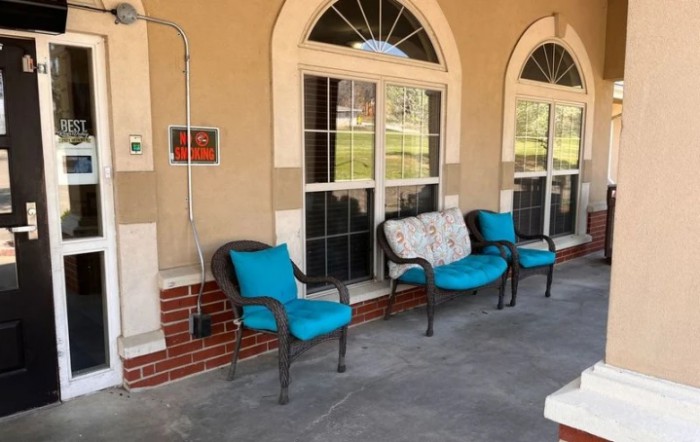 A cozy patio area with turquoise cushioned chairs and arched windows.
