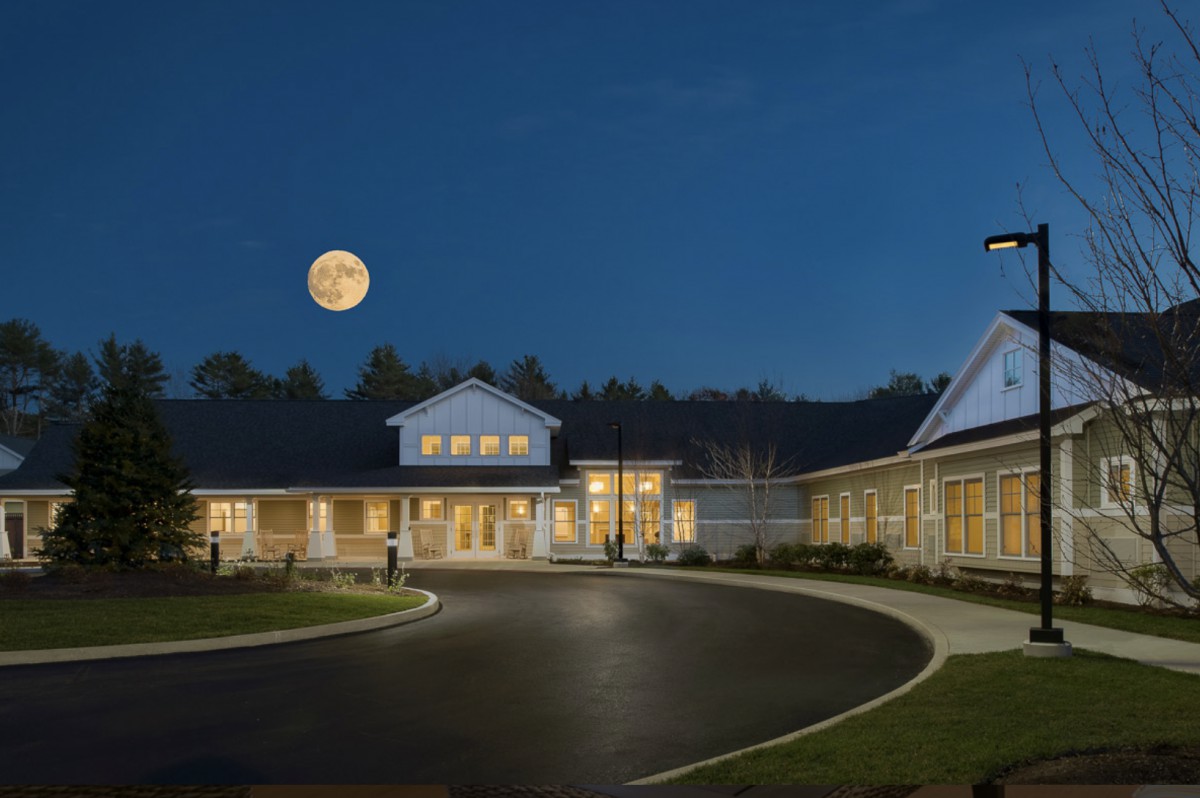 A building with a circular driveway is illuminated under a full moon at night.
