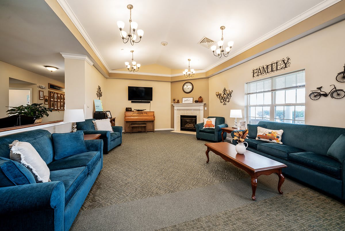 A cozy living room with blue sofas, a wooden coffee table, and a fireplace beneath a television.