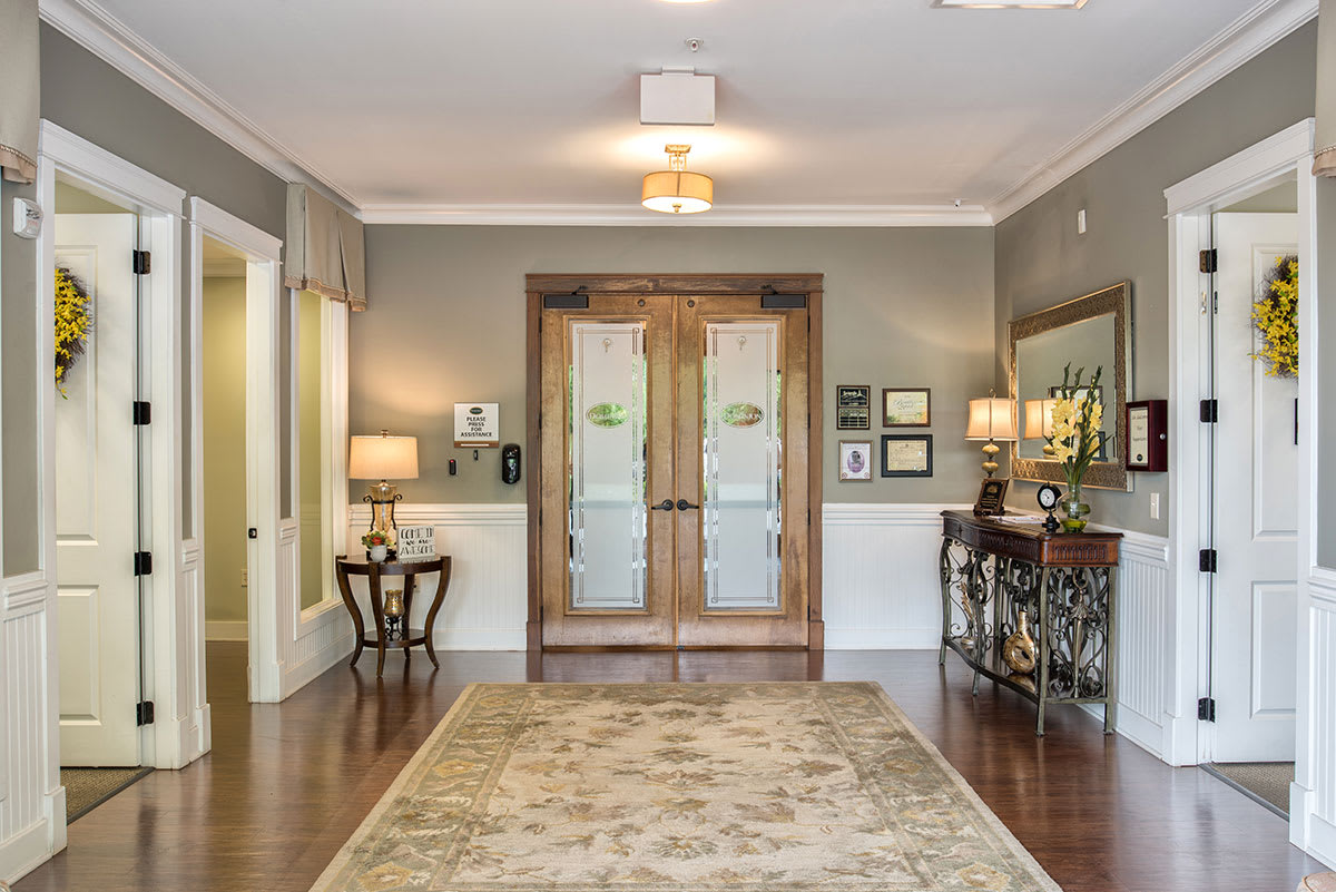 A beautifully decorated entrance foyer with wooden doors, a decorative rug, and elegant lamps.