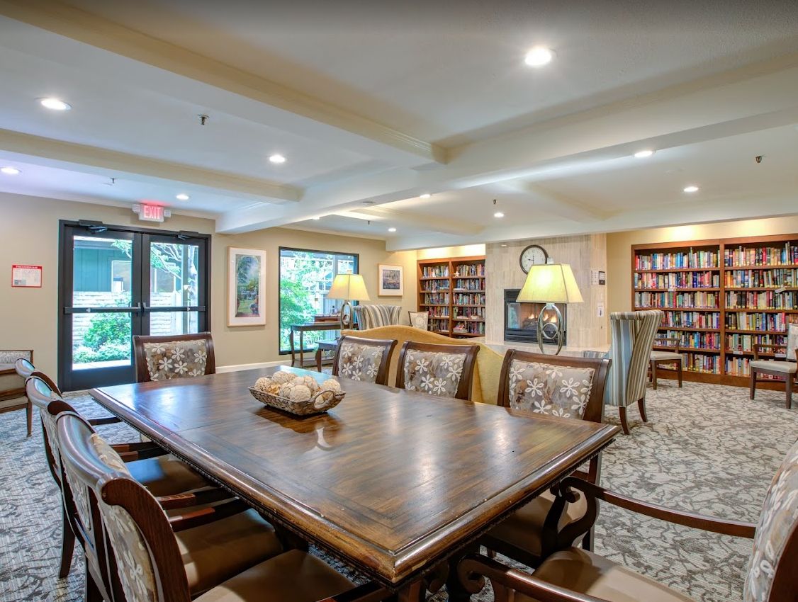 A cozy library reading room with a large table and bookshelves.
