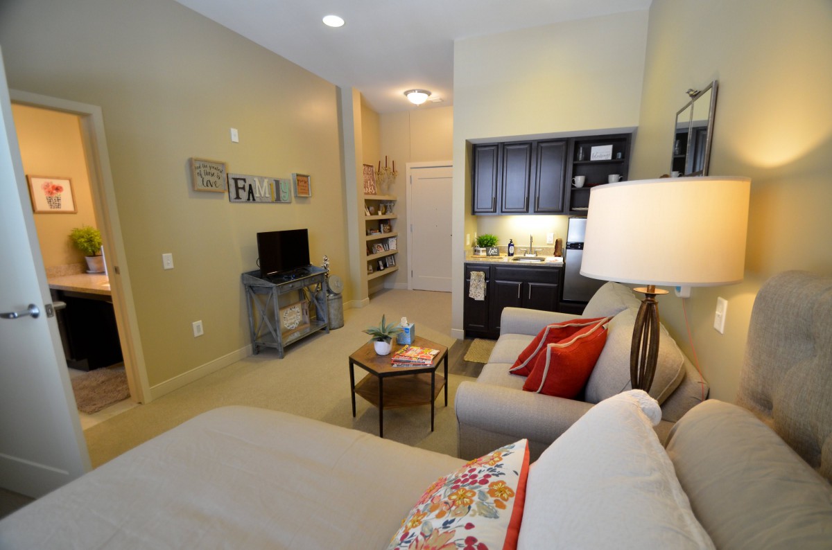 A cozy studio apartment with a modern interior design, featuring a living area and a small kitchenette.