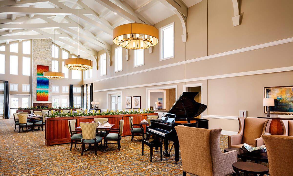 A spacious and elegant lounge with a grand piano, comfortable seating, and stylish chandeliers.