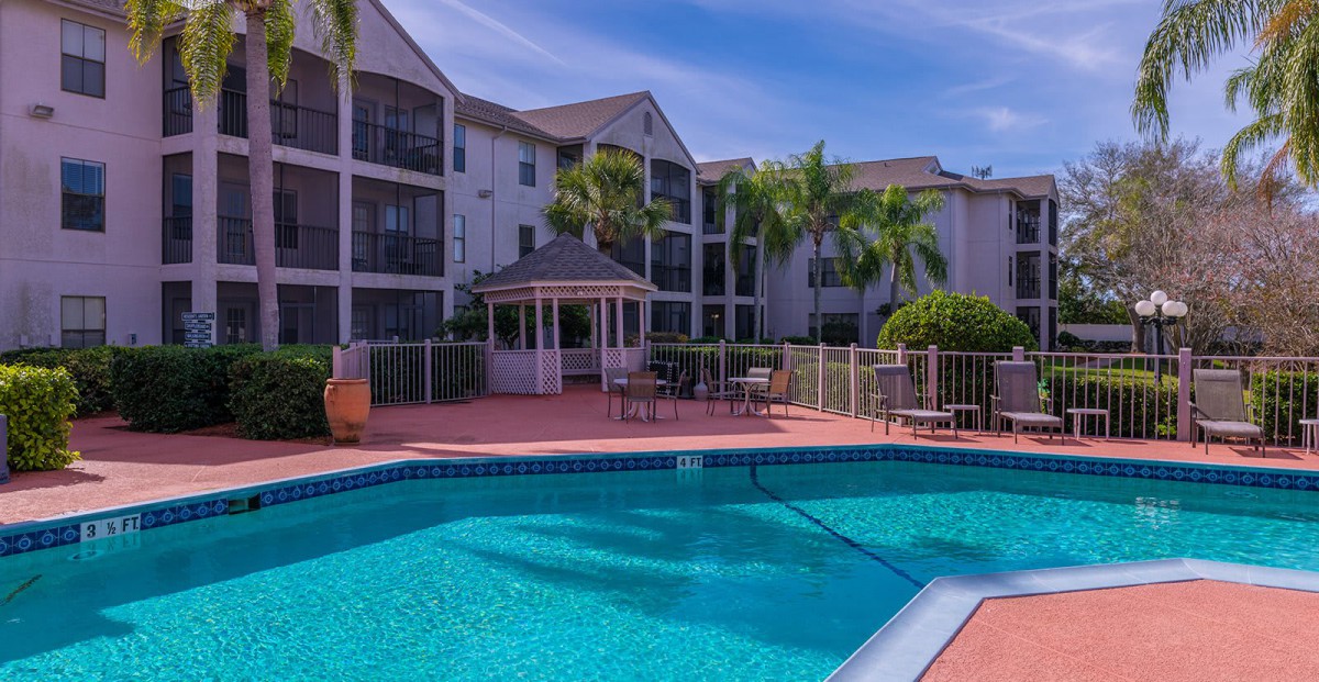 A residential complex with a swimming pool and palm trees.