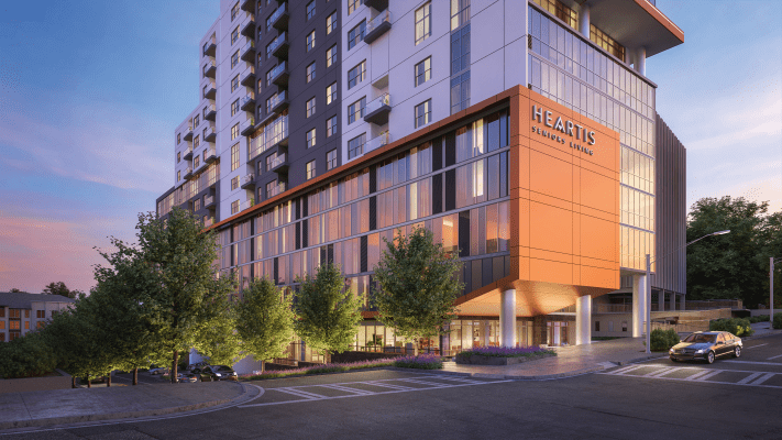 A modern hotel building with a sleek design and surrounding trees.