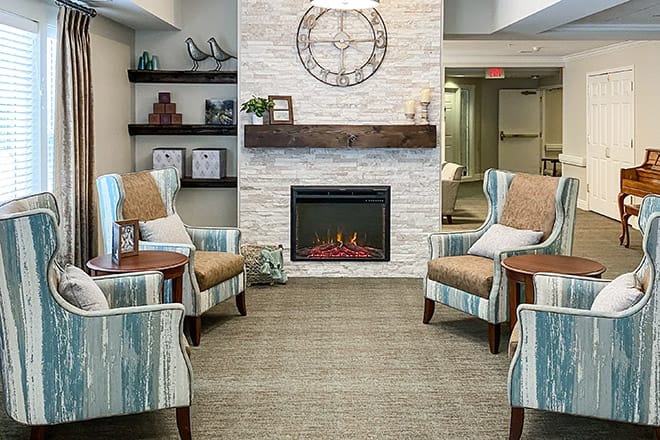 A cozy living room with armchairs and a modern fireplace set against a stone wall.