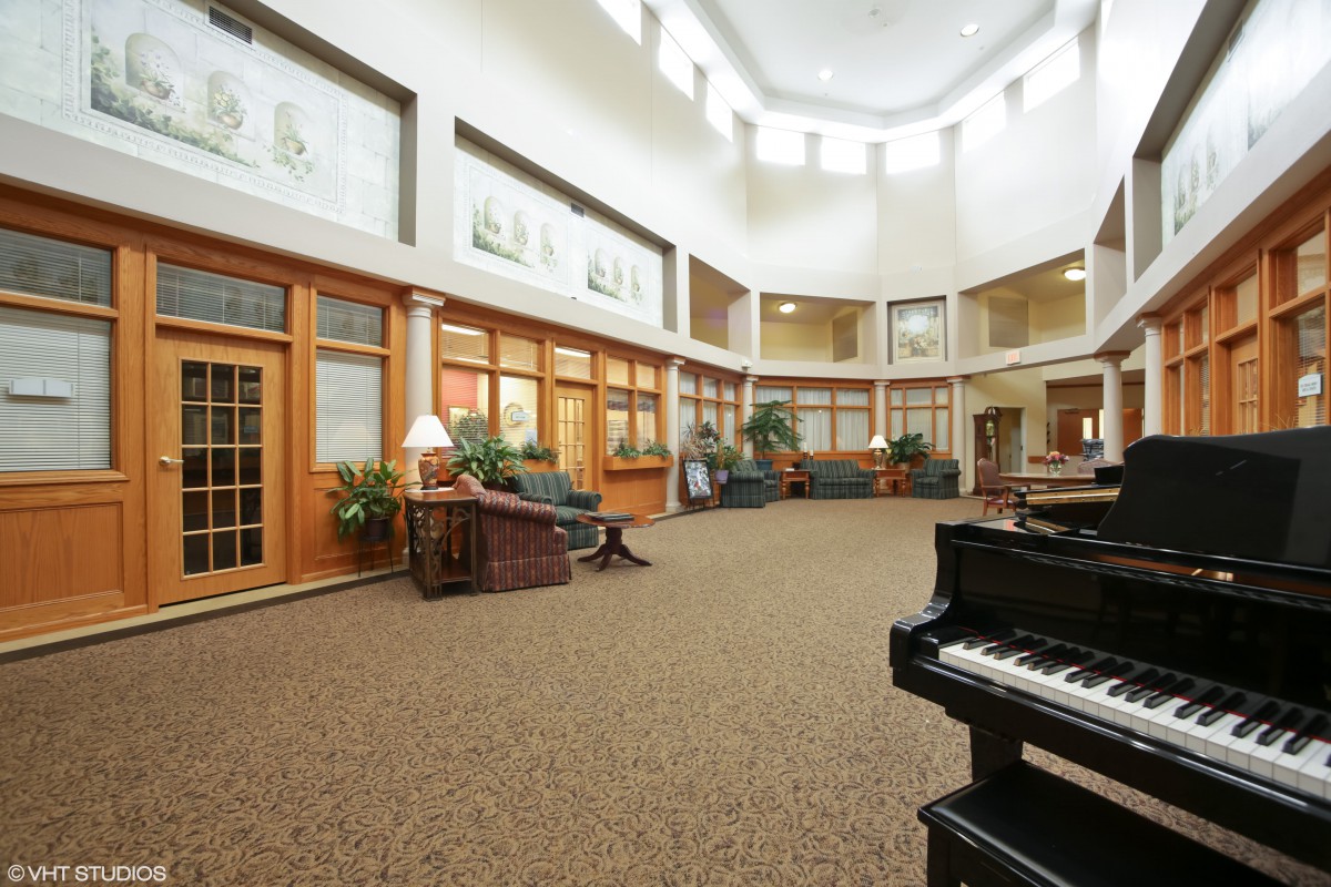 A spacious lobby with a grand piano, comfortable seating, and large windows allowing natural light.