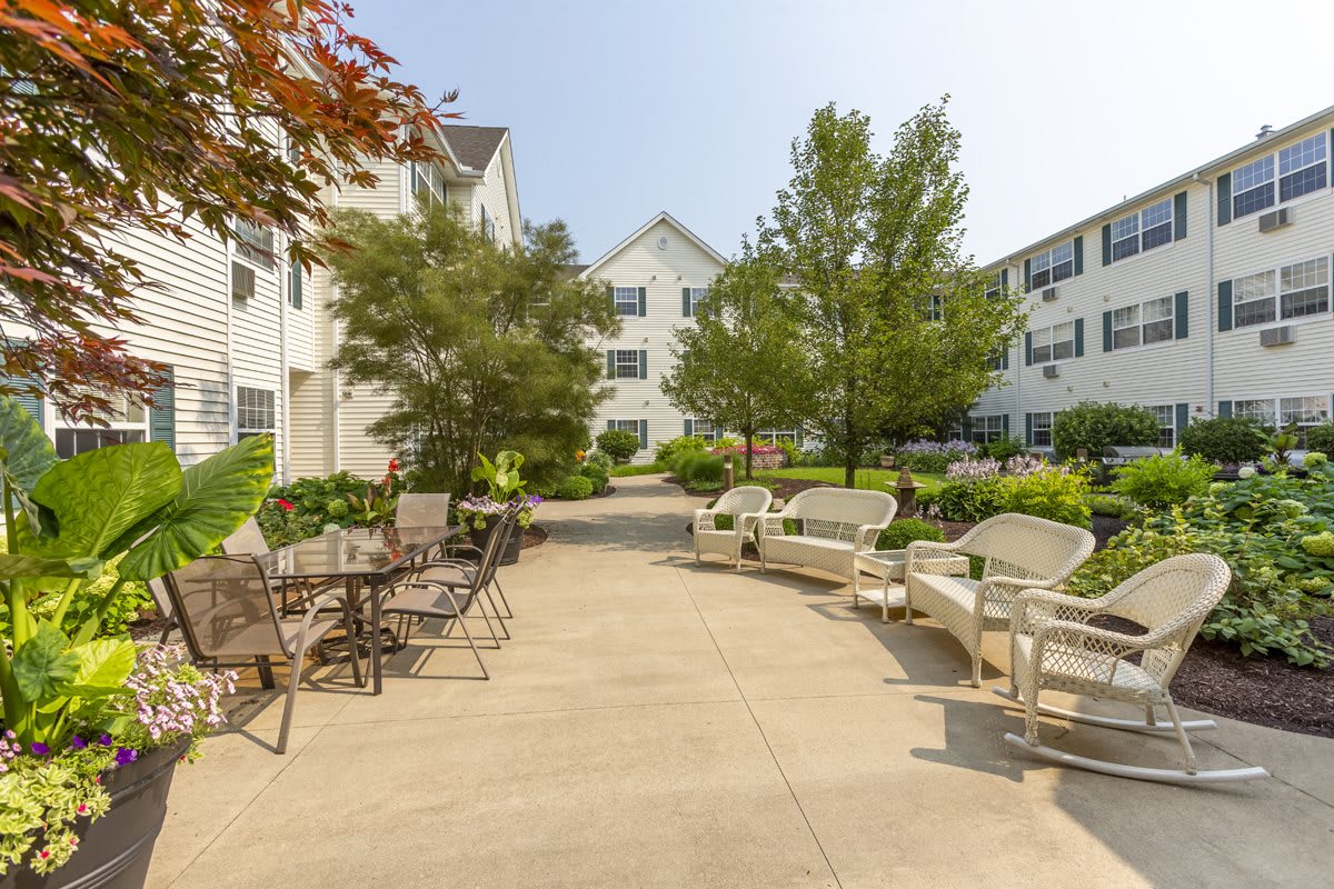 A cozy outdoor patio area with chairs and tables surrounded by trees and apartment buildings.
