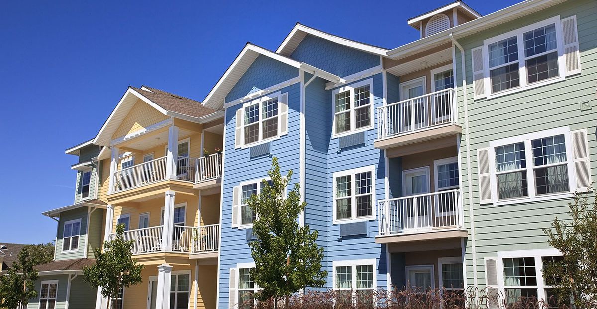 A modern apartment building with vibrant blue and yellow exteriors, featuring multiple balconies.