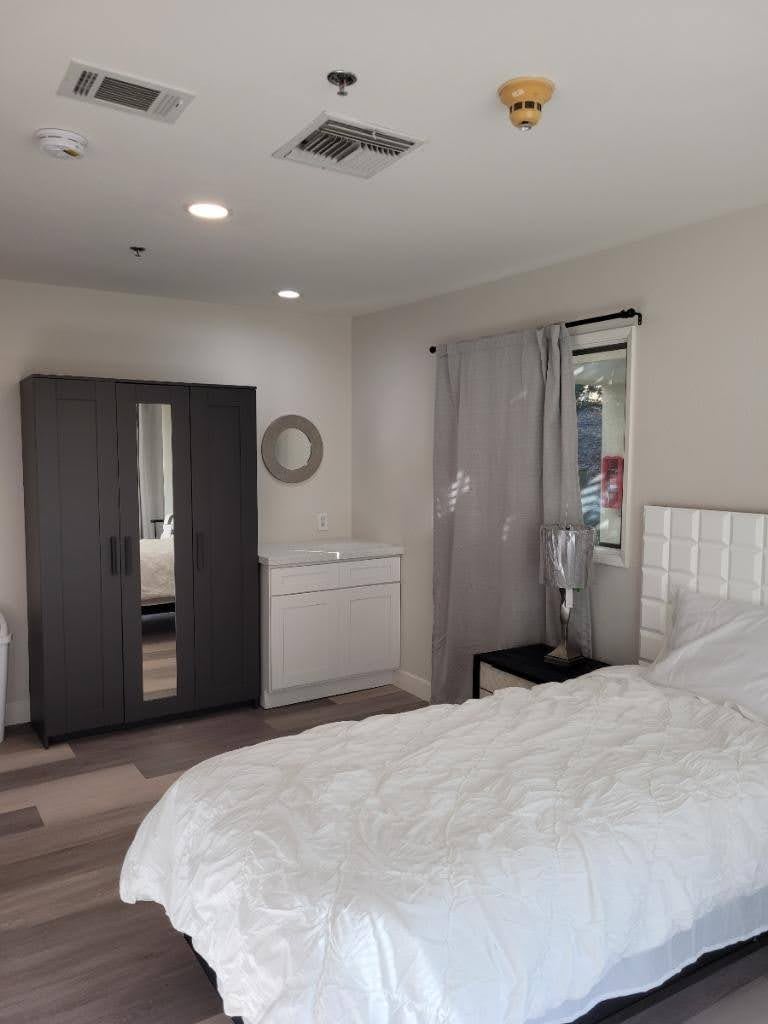 A modern bedroom with a bed, wardrobe, and mirror.