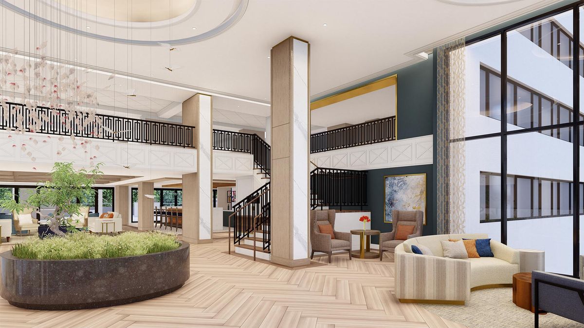 A modern hotel lobby featuring stylish furniture and a central staircase.