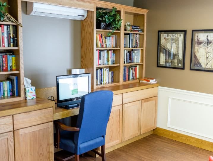 A tidy home office with a computer, bookshelves, and a comfortable chair.