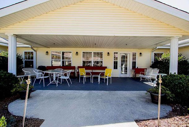 A cozy outdoor patio with tables and chairs set up under a covered area.