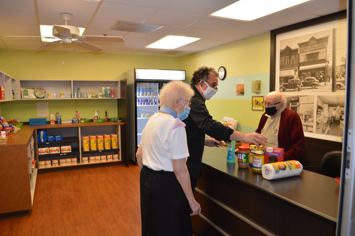 People shopping at a grocery store counter while wearing masks.
